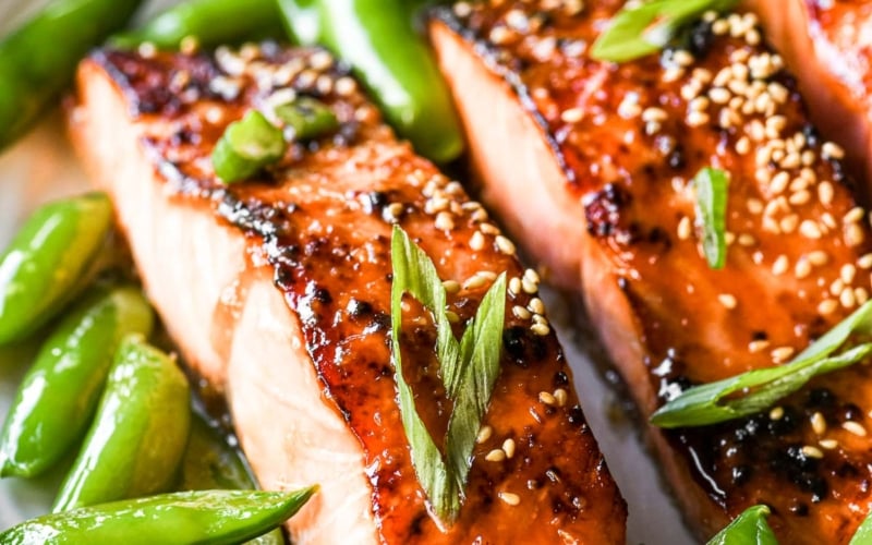 Miso glazed salmon on a plate with pea pods.