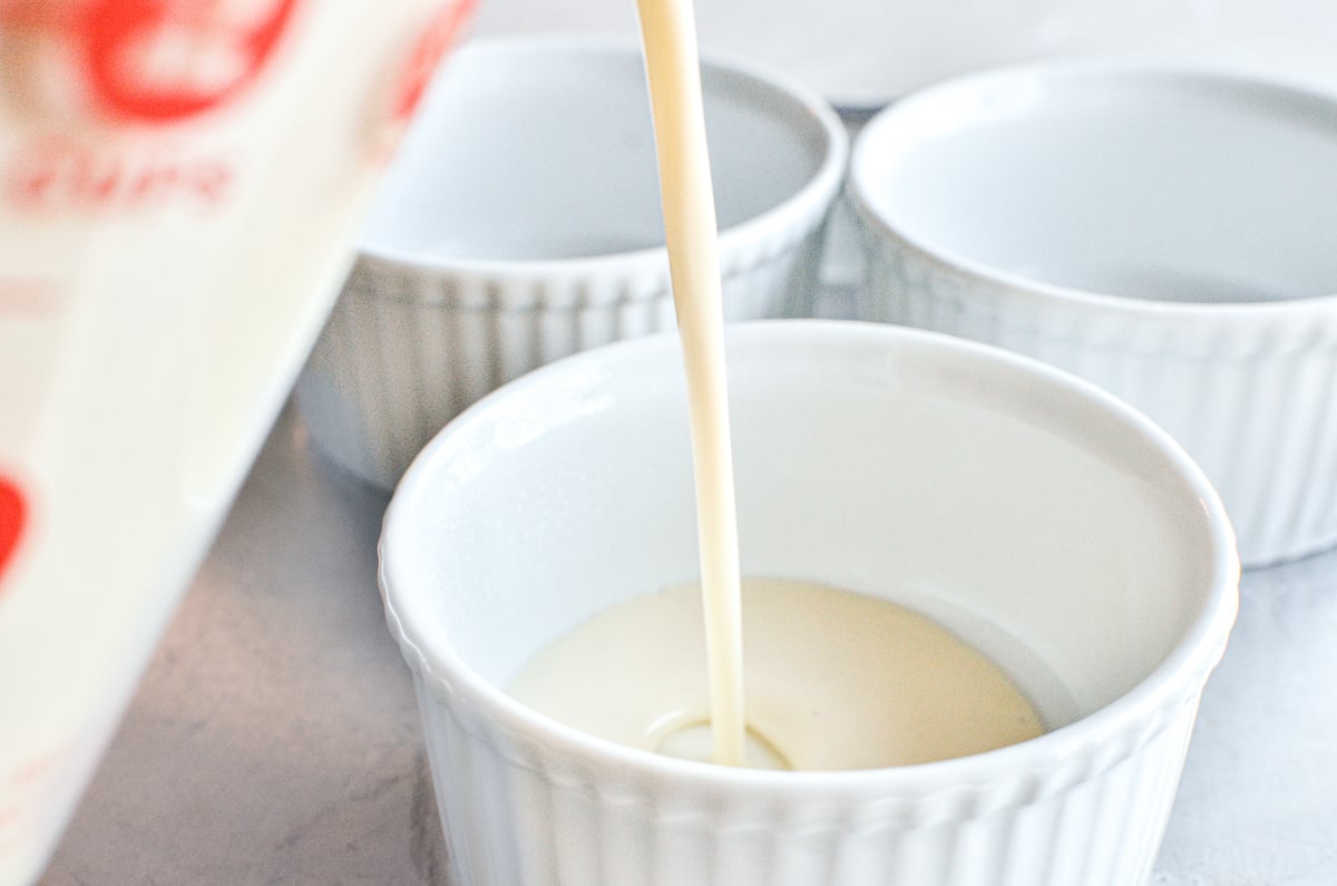 pouring panna cotta into individual ramekins.