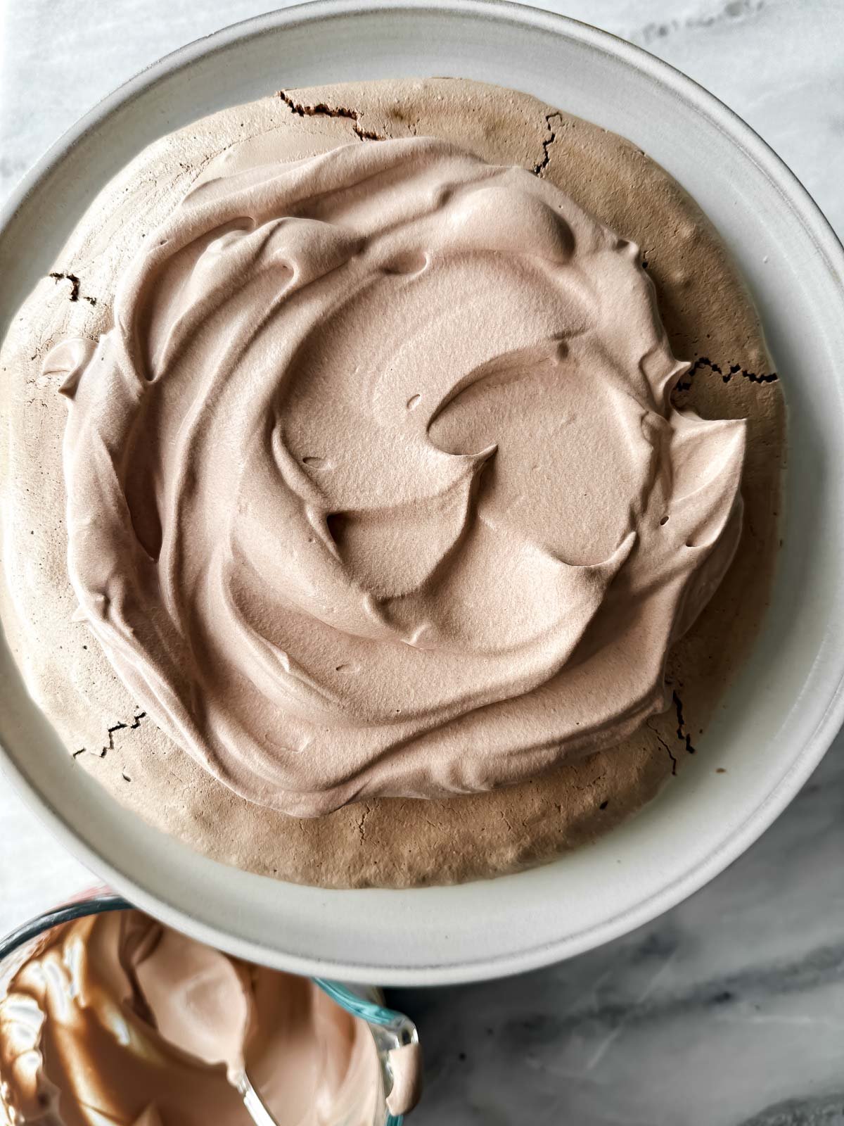 Topping a chocolate pavlova with chocolate whipped cream.