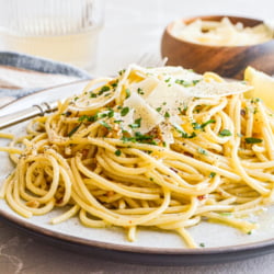 Pasta with oil and garlic on a plate with cheese and parsley.