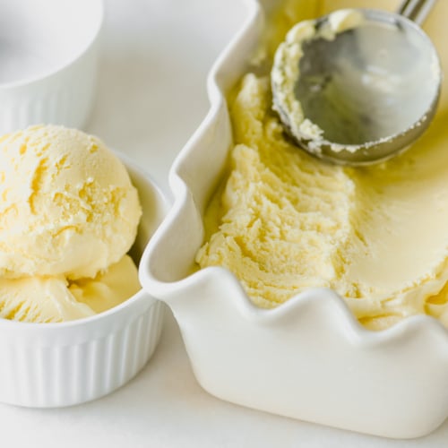 lemon frozen custard being scooped into a small bowl.