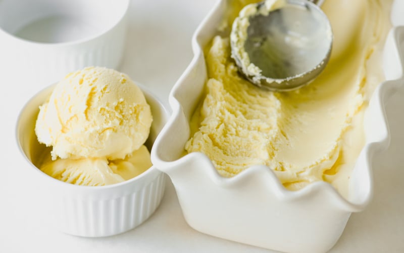 lemon frozen custard being scooped into a small bowl.