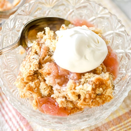 A bowl of rhubarb dump cake with whipped cream.