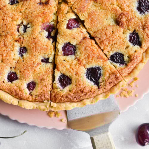 A cherry almond tart, with slice being taken.