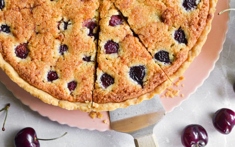 A cherry almond tart, with slice being taken.