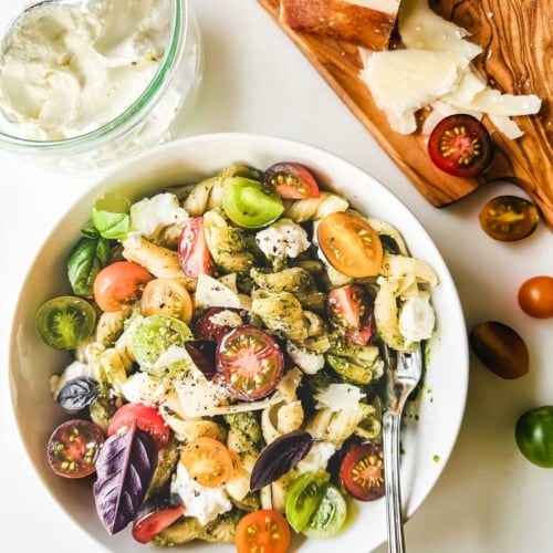 Pasta with pesto, ricotta, and heirloom cherry tomatoes in a bowl.