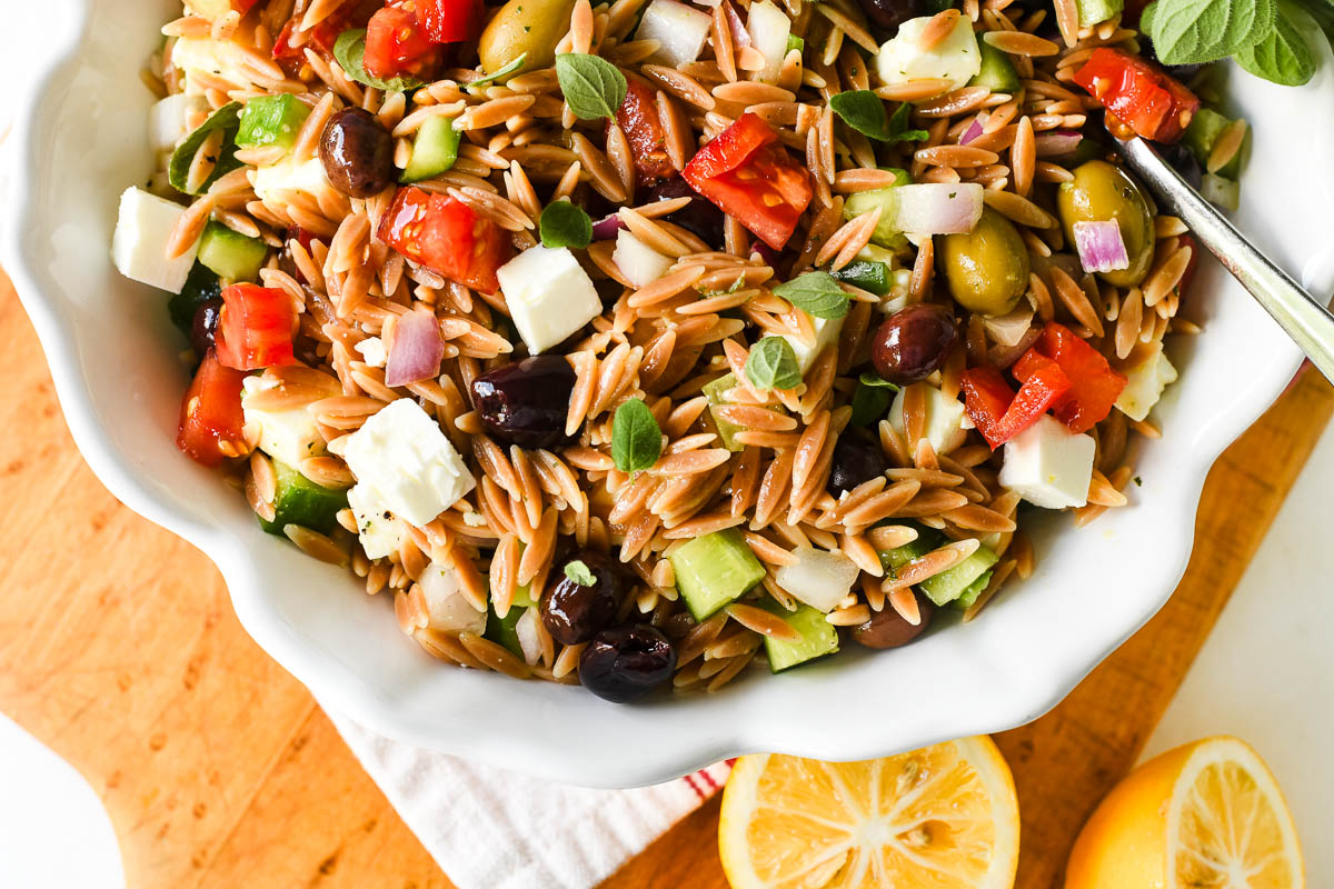 Greek Toasted Orzo Salad in a bowl with serving spoon.