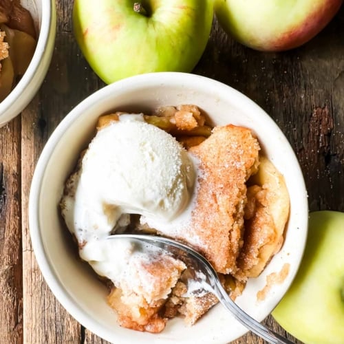 cider doughnut apple cobbler in a bowl with ice cream.