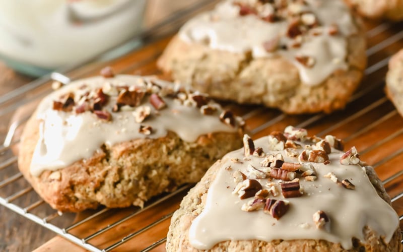 Glazing maple oat nut scones on a rack.