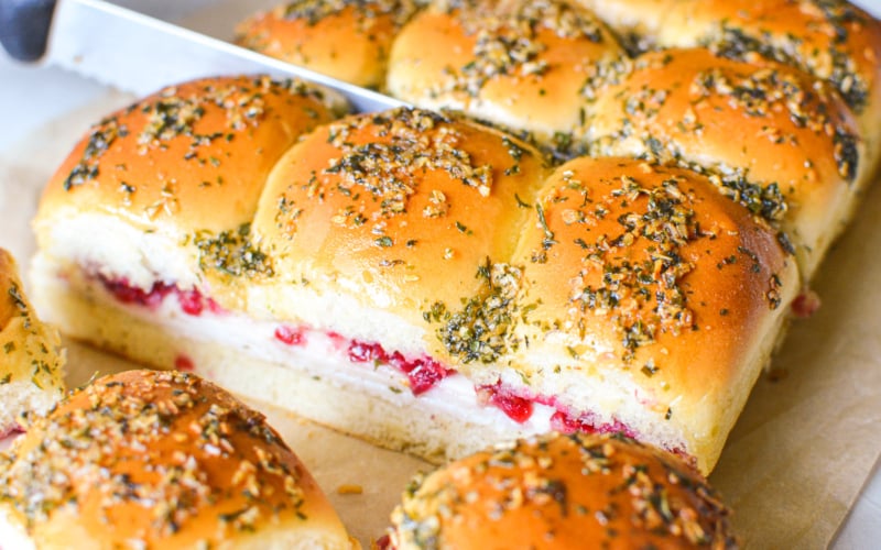 Cutting apart turkey cranberry sliders.