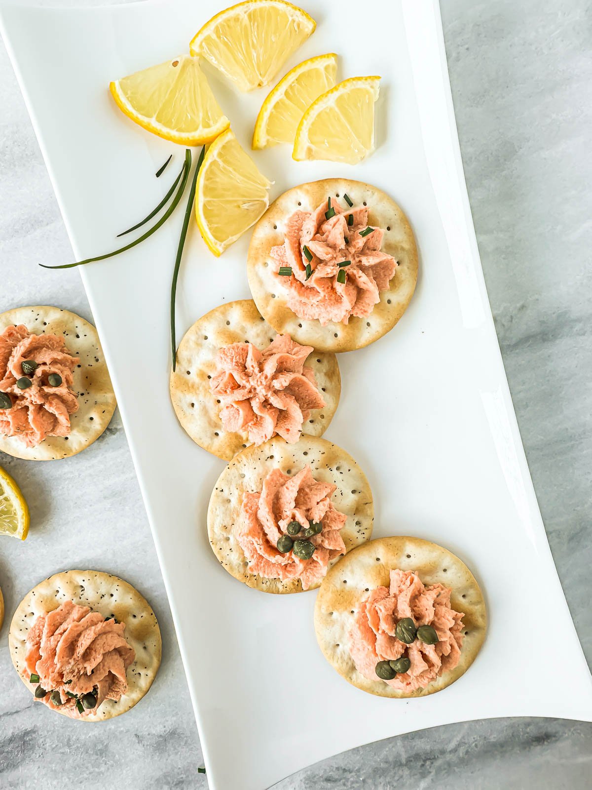 smoked salmon piped on crackers, on a tray.