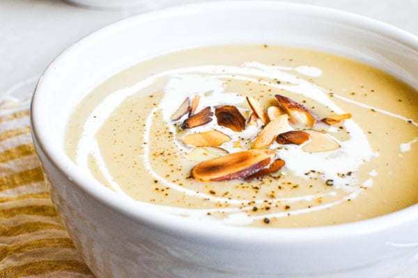 a bowl of parsnip soup garnished with cream and almonds.