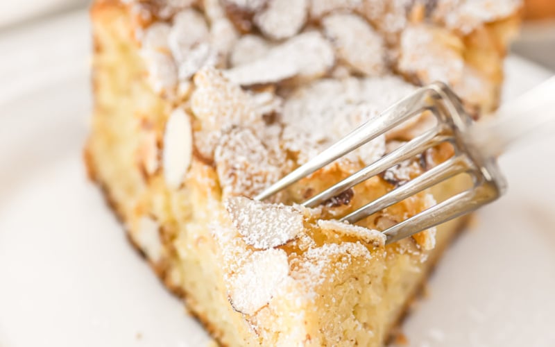 taking a bite of a slice of almond croissant cake.