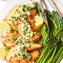 crispy chicken with artichoke salsa on an oval platter with asparagus.