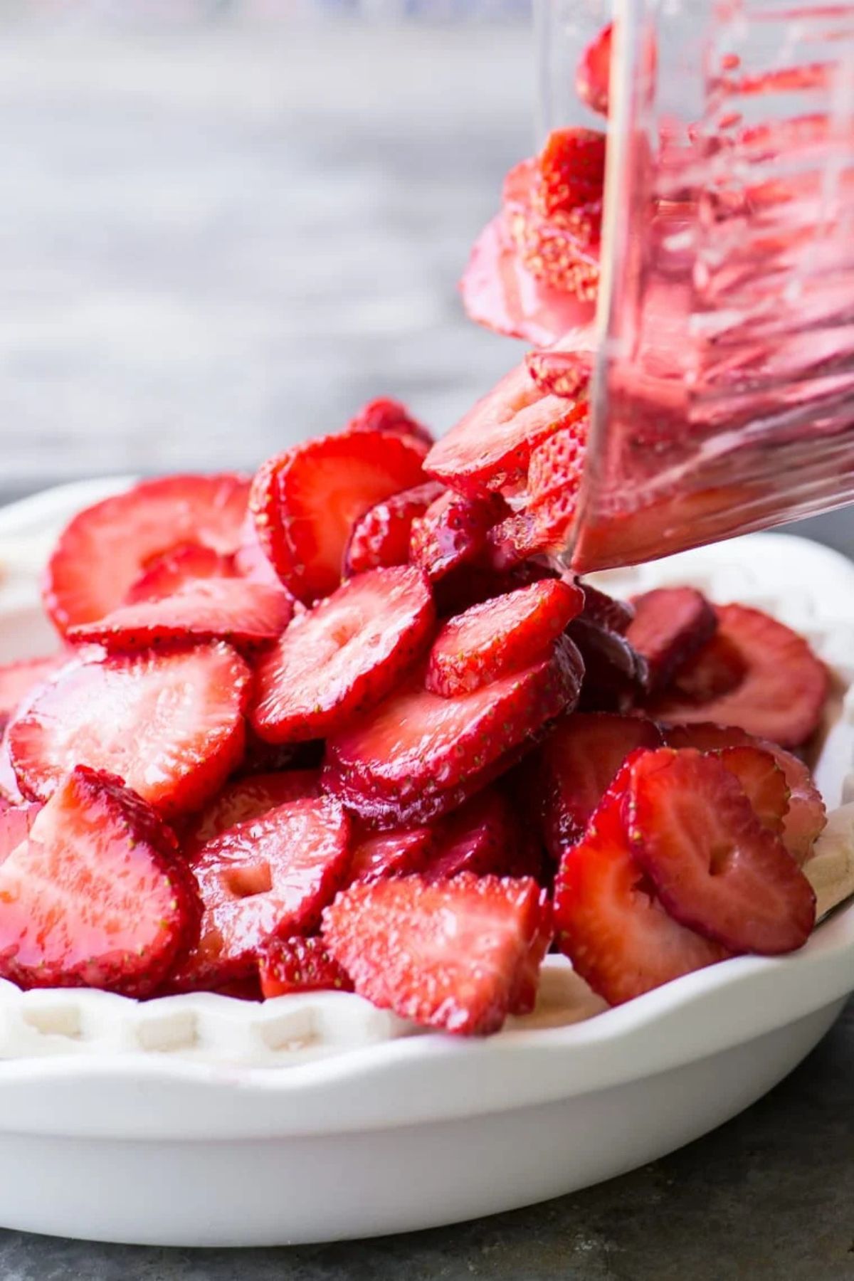 tumbling strawberries into a pie crust for strawberry pie.