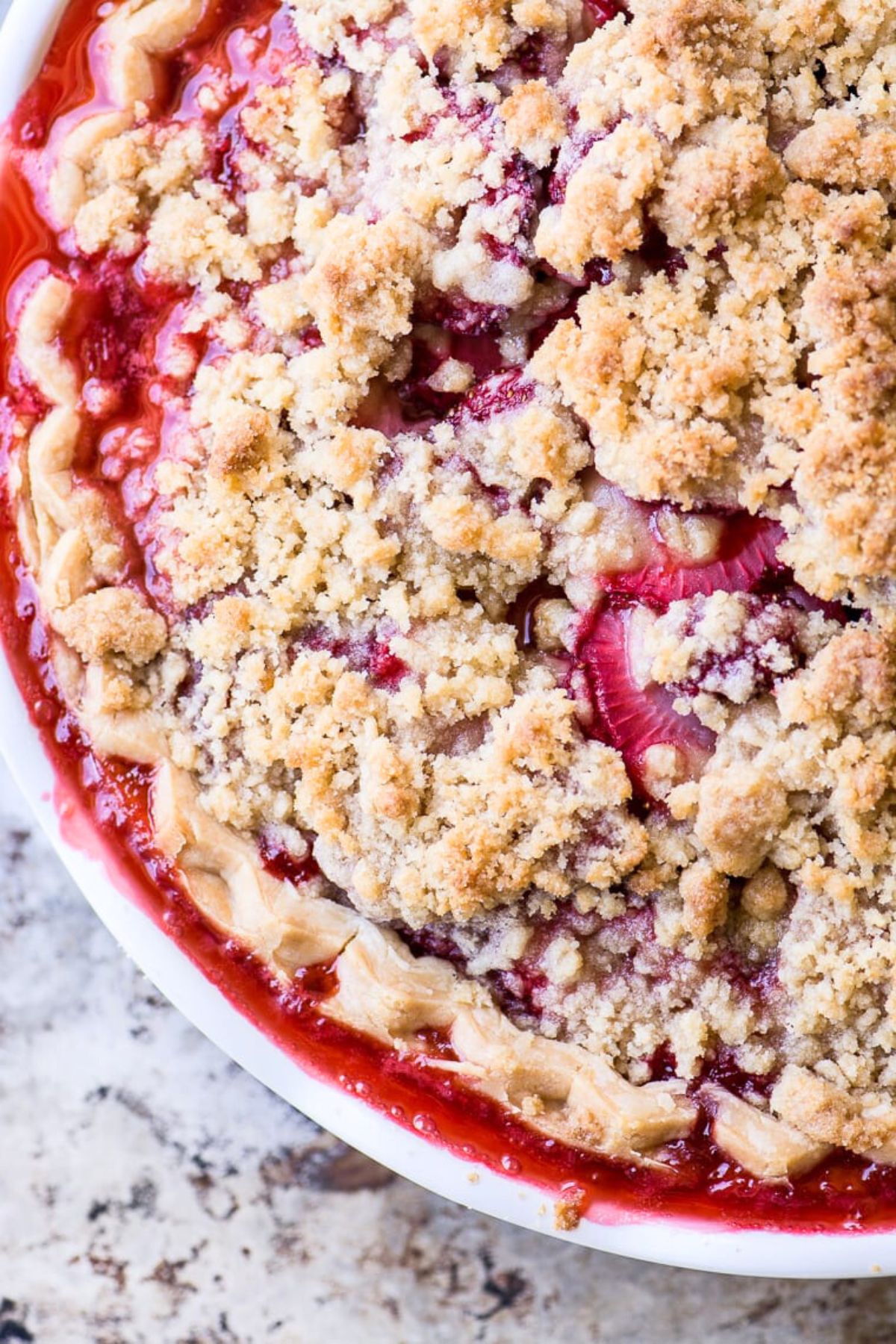 Overhead look at a strawberry pie with golden crumble topping.