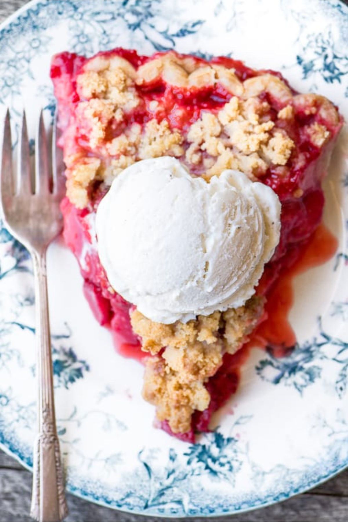 a slice of strawberry crumble pie, with a scoop of ice cream.