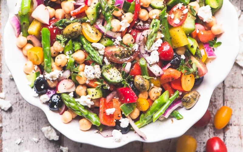 Colorful and crunchy asparagus salad in a white bowl on a wooden table.
