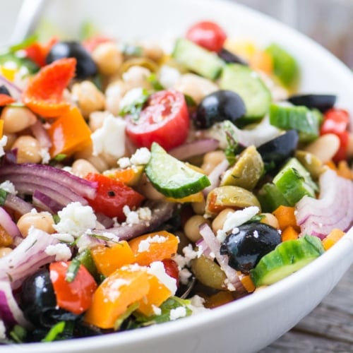 Mediterranean bean salad in a white serving bowl.
