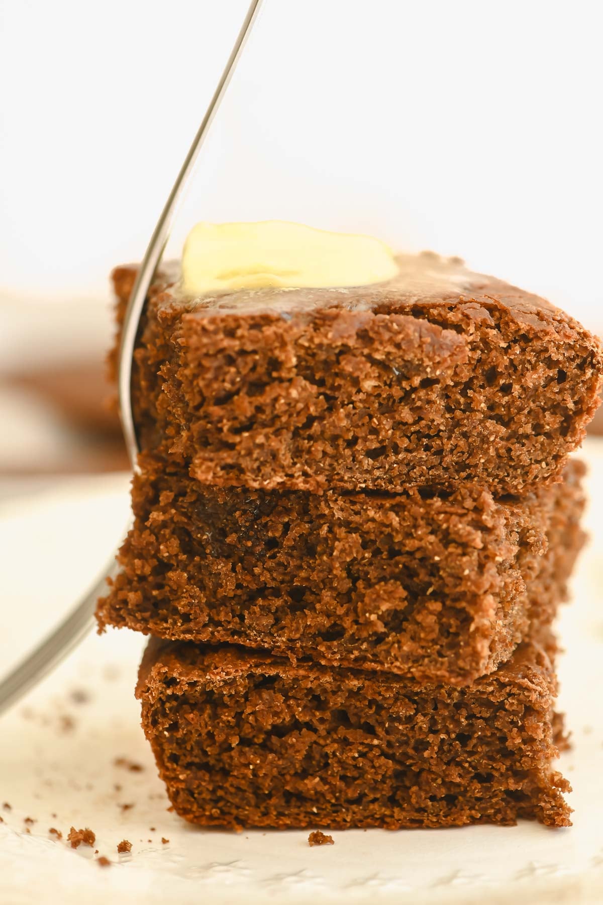 molasses cornbread, stacked, with butter and fork.