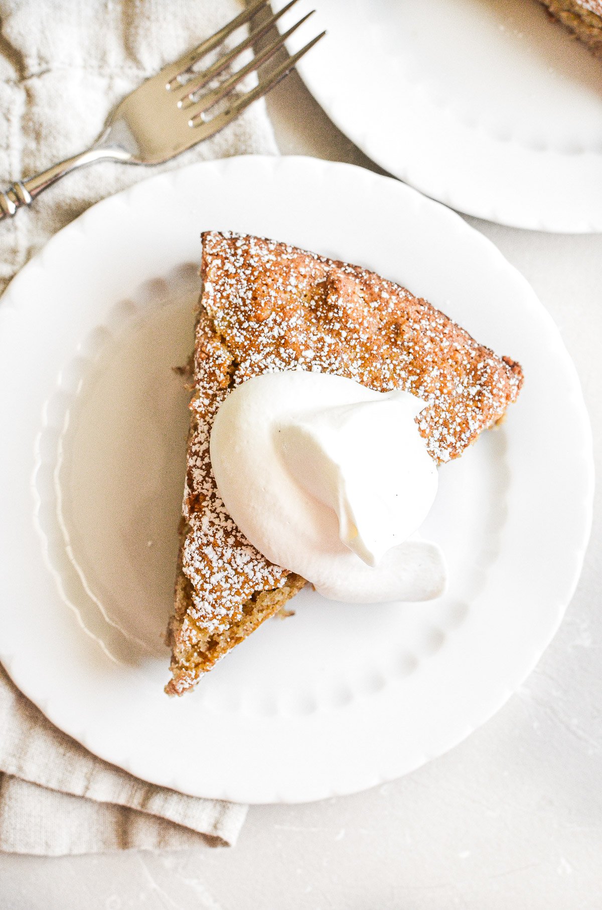 A slice of almond flour banana cake topped with whipped cream.