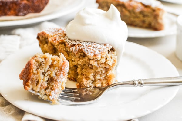 taking a bite of a slice of almond flour banana cake, topped with whipped cream.