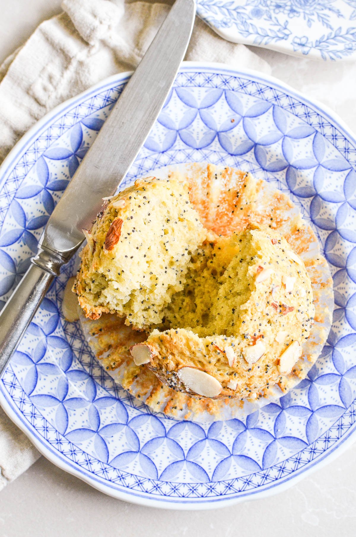 Almond poppy seed muffin broken open on a plate.