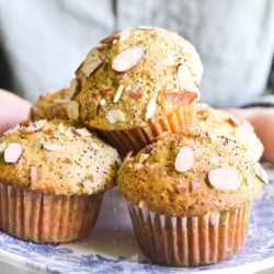 holding a plate of almond poppy seed muffins.