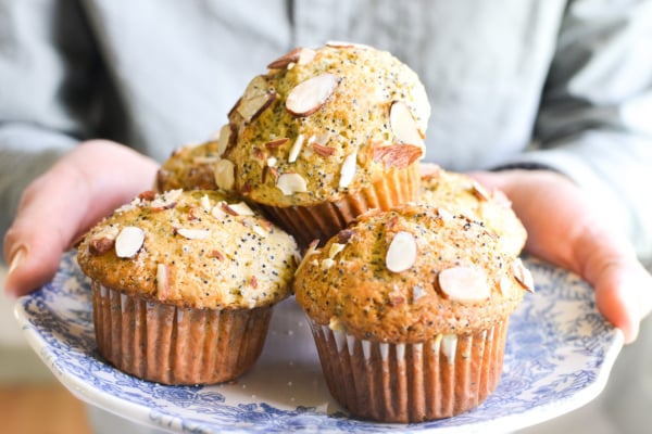 holding a plate of almond poppy seed muffins.