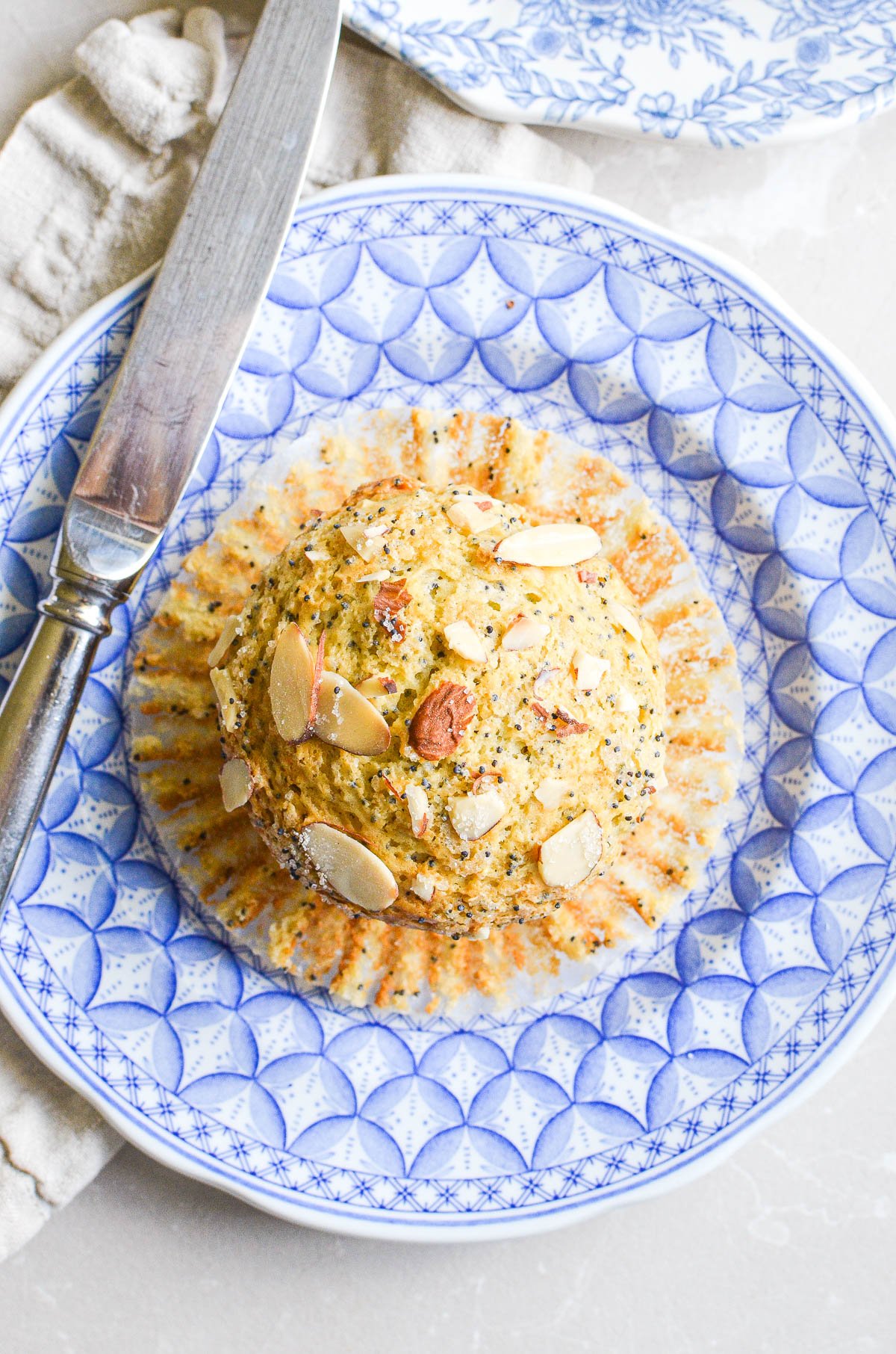 An almond poppy seed muffin unwrapped on a blue plate.