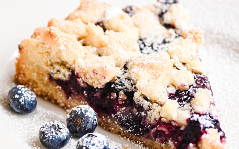 a slice of blueberry lemon crumble tart, with blueberries.