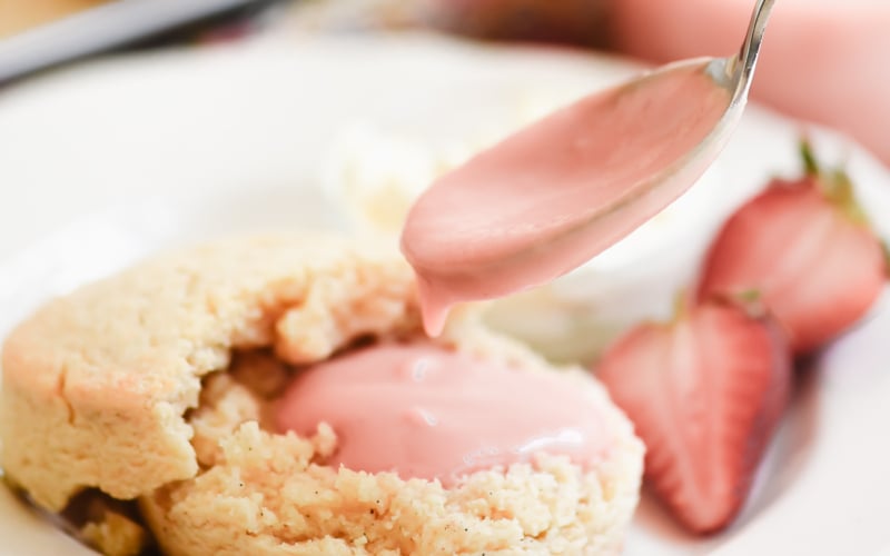 Spooning strawberry curd onto a vanilla scone.
