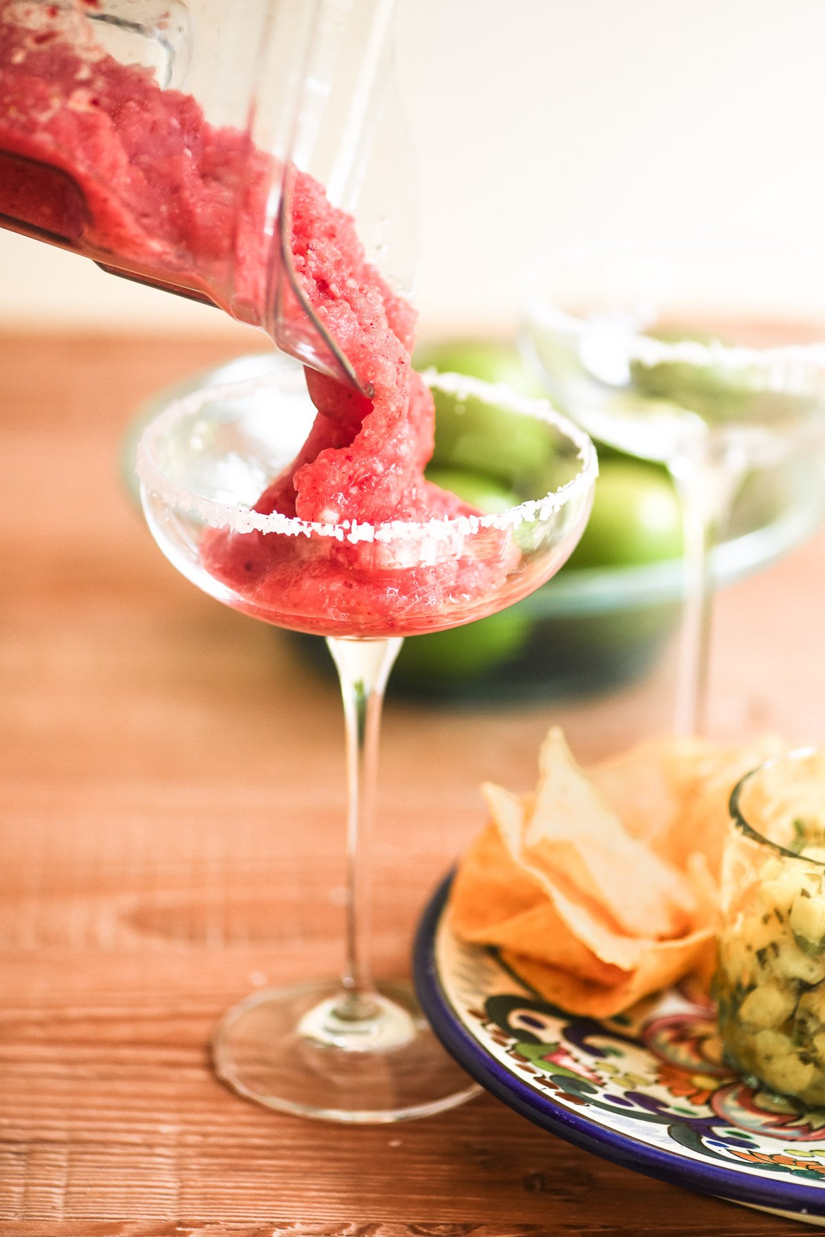 Pouring frozen strawberry rhubarb margarita into a glass.