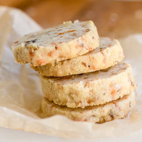 a stack of cheddar walnut shortbread crackers on parchment paper.