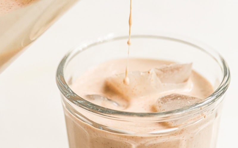 pouring horchata into a glass with ice.