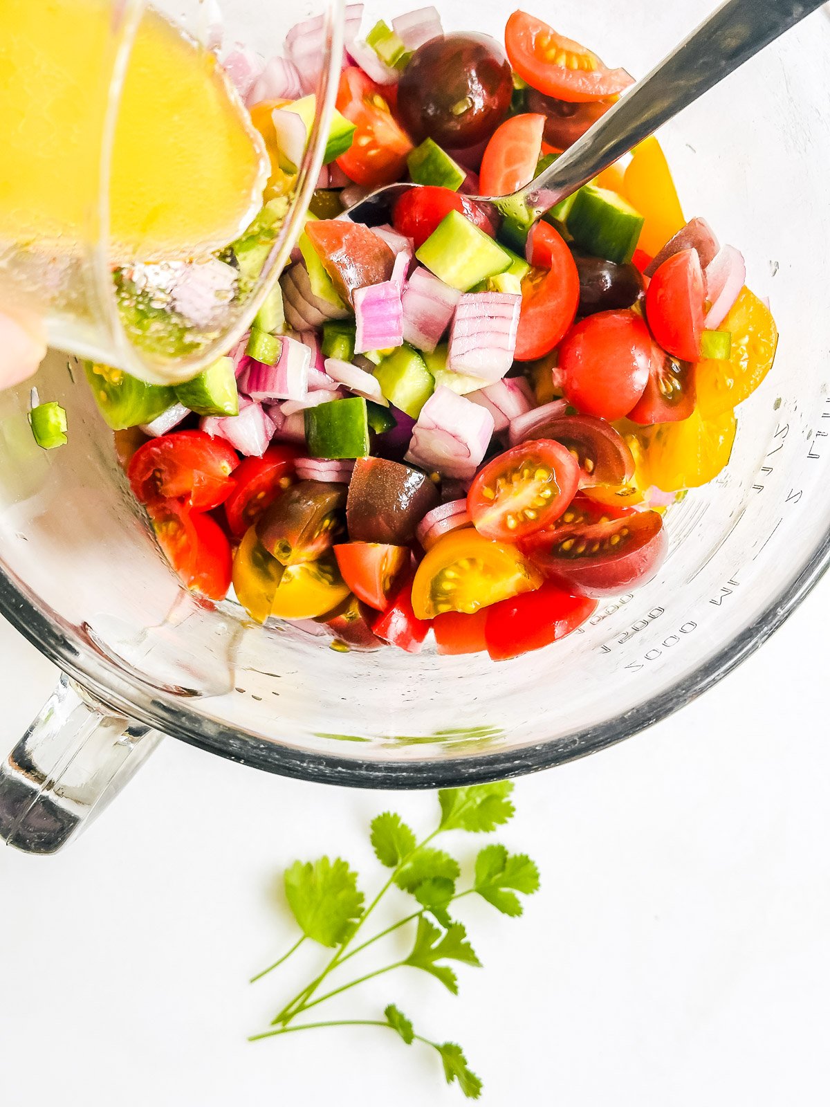 pouring lime dressing onto pico de gallo salad