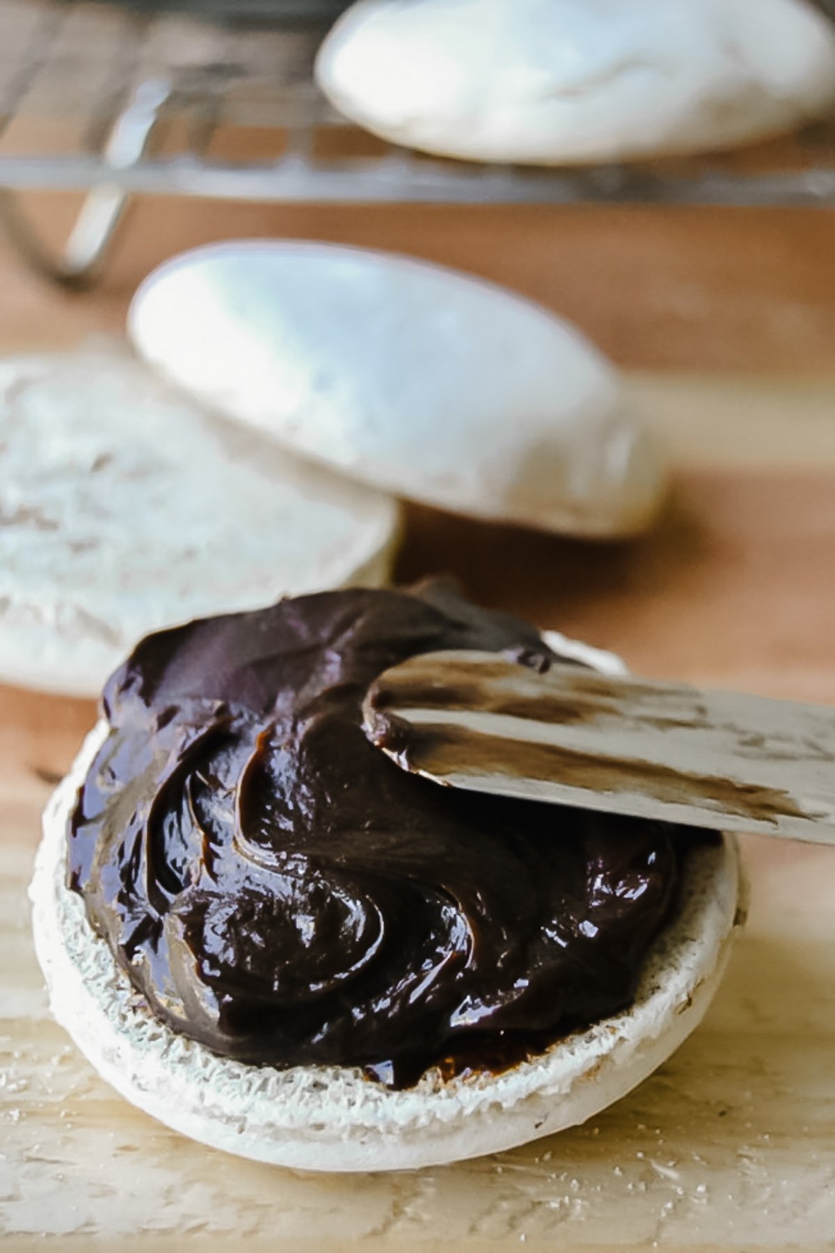 spreading ganache on a meringue cookie for Sarah Bernhardt cookies.