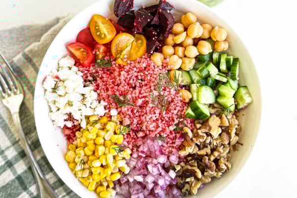 summer couscous salad in a white bowl with lemon dill dressing.