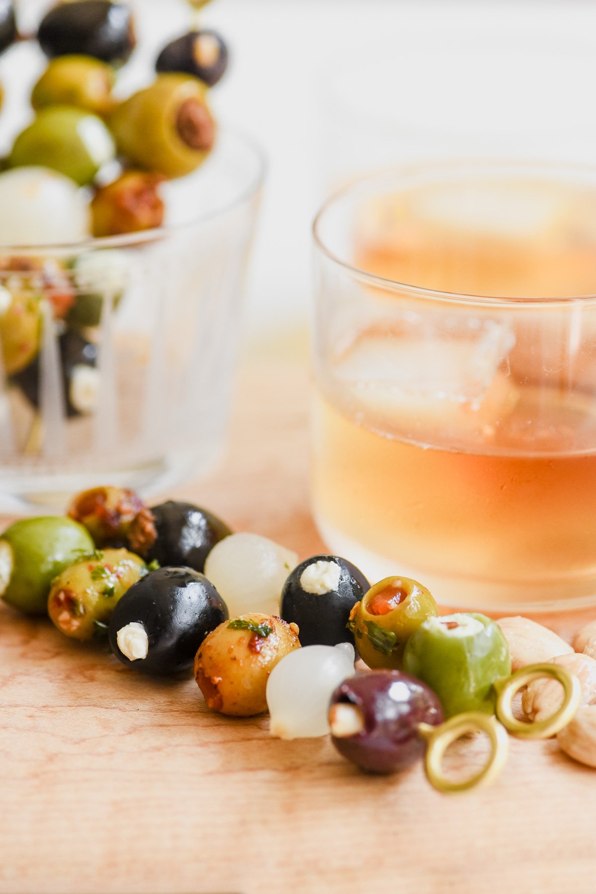 stuffed olive cocktail picks, on a board with drink.