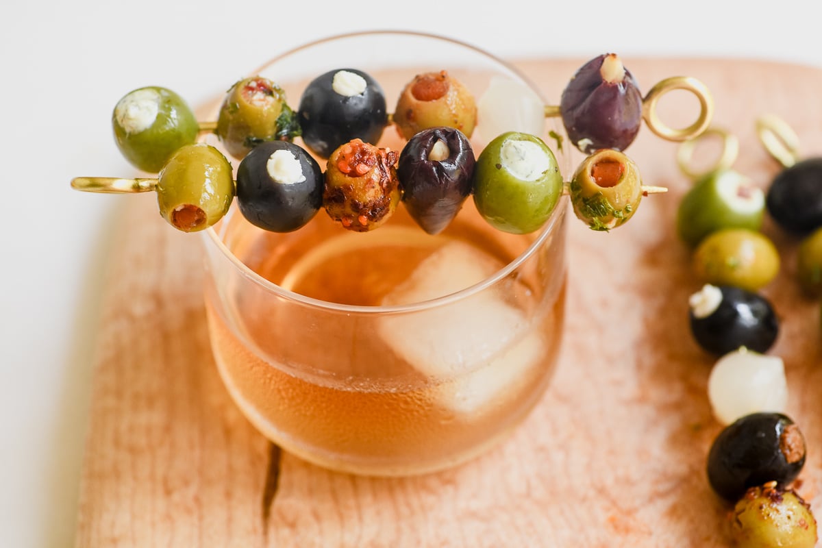 stuffed olive picks on a wooden board with cocktail.