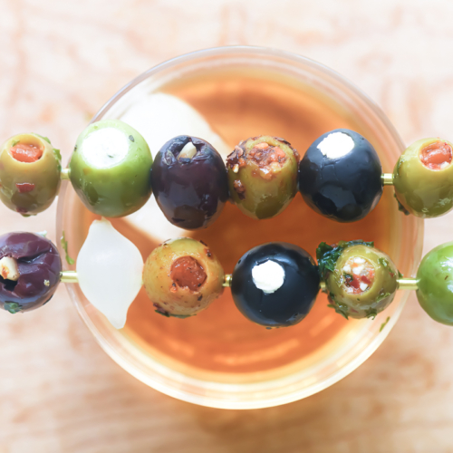 stuffed olive cocktail picks on a cocktail glass.