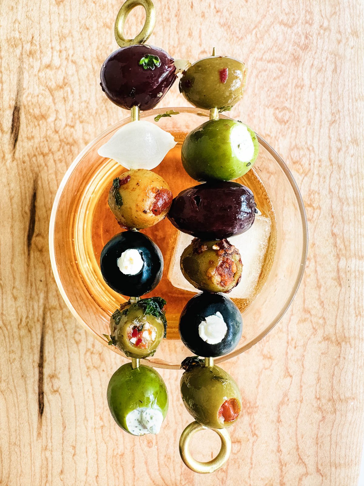 stuffed olive oil cocktail picks on a cocktail glass.