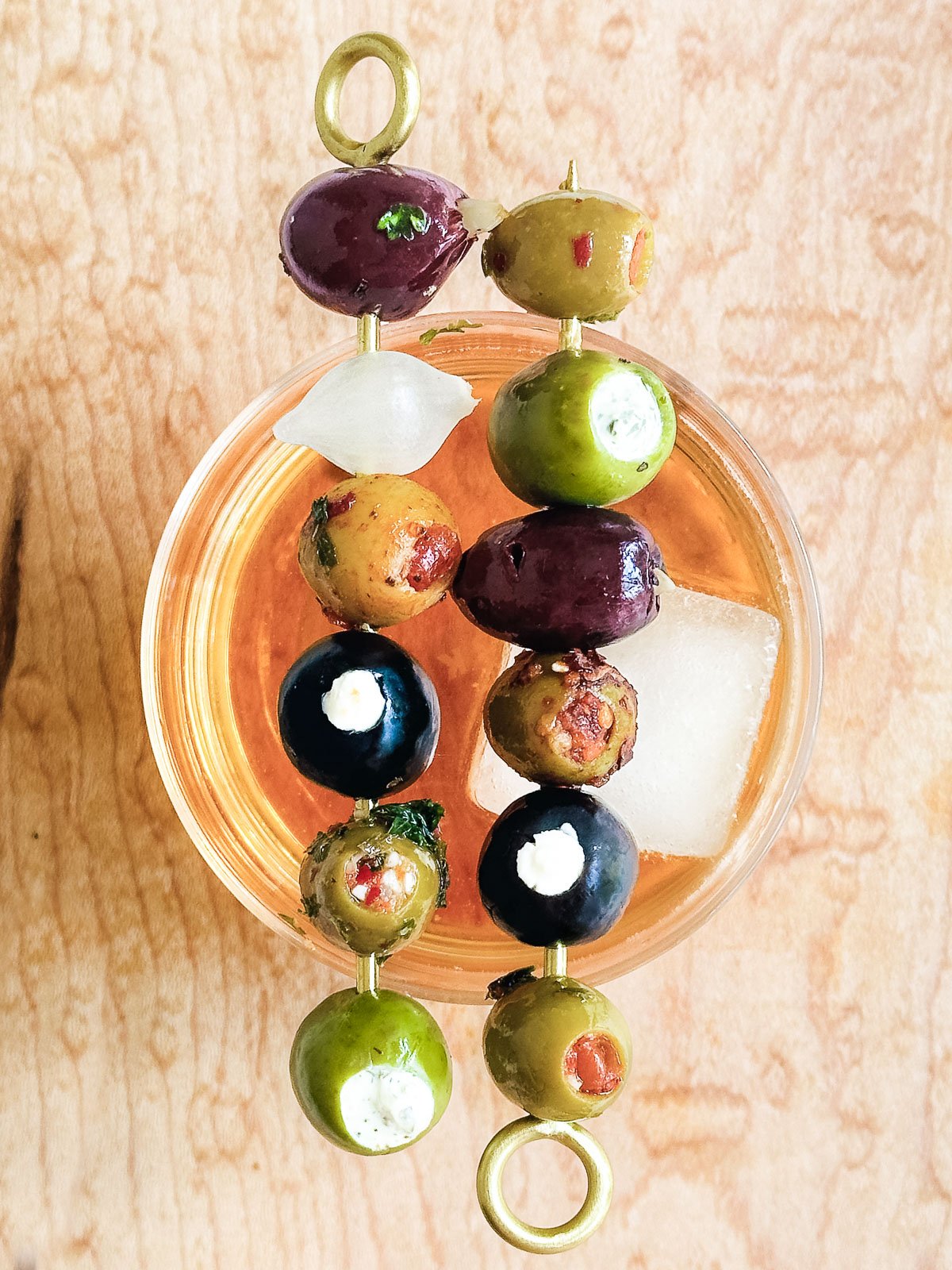 stuffed olive cocktail picks, on a cocktail glass.