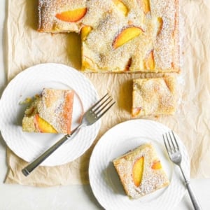 serving almond peach cake on white plates with forks.