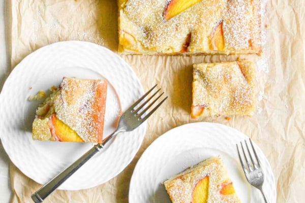 serving almond peach cake on white plates with forks.