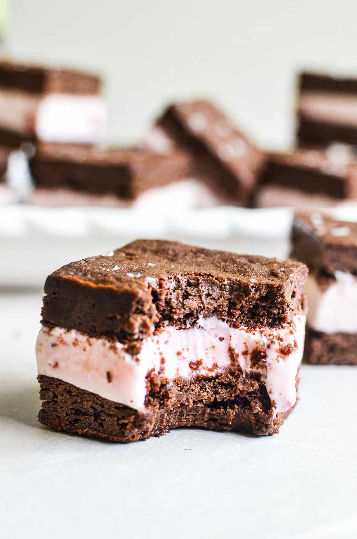 A brownie ice cream sandwich with a bite taken out.