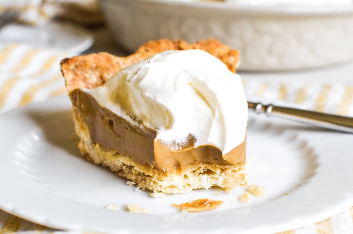 A slice of butterscotch pudding pie with a bite taken out.