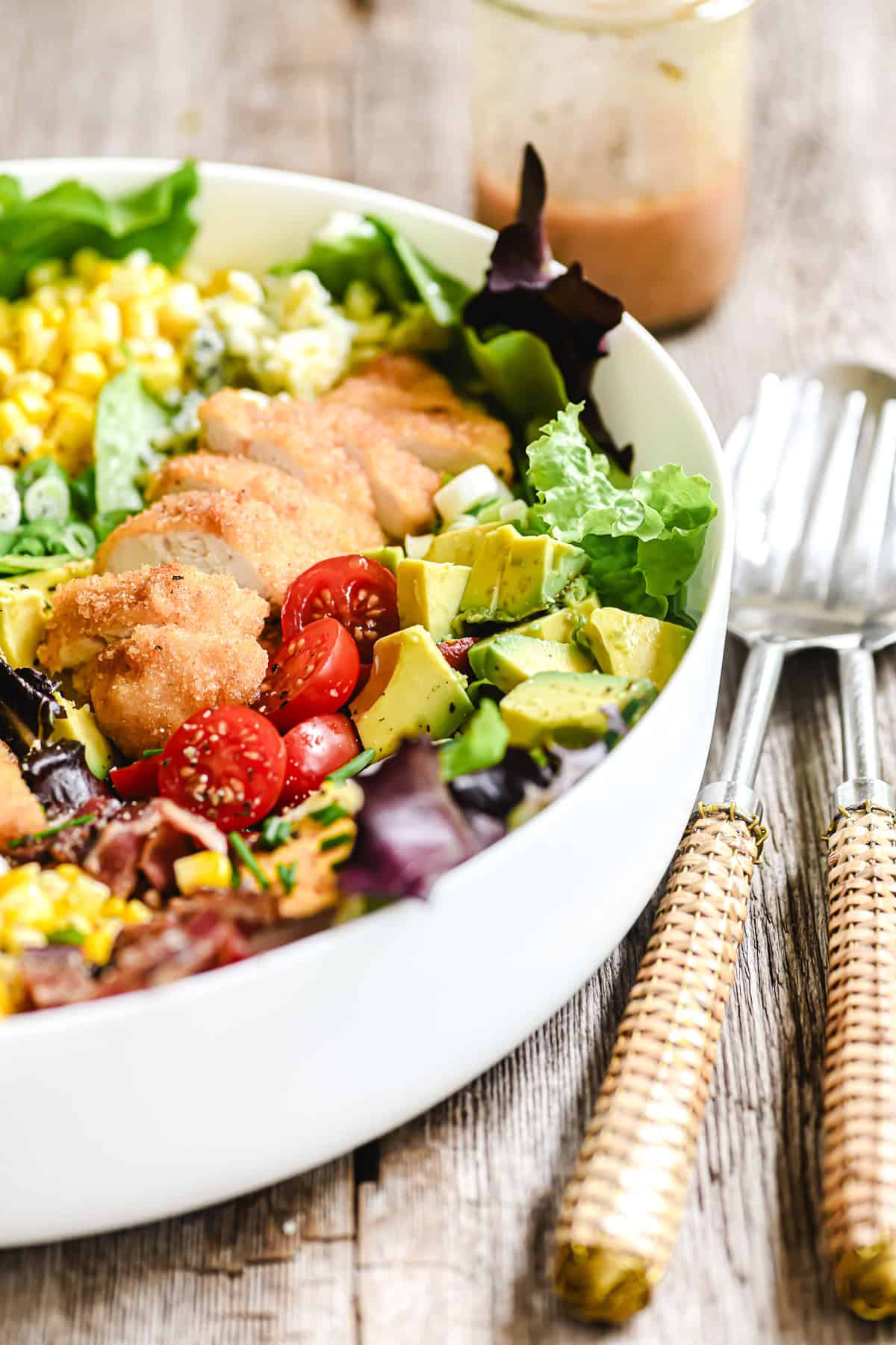 fried chicken cobb salad in a large white serving bowl.