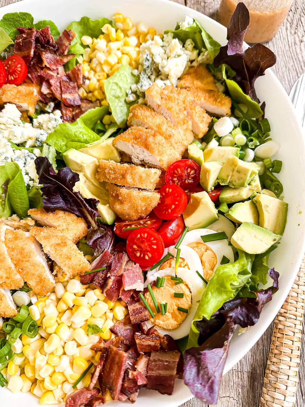 fried chicken cobb salad composed in a white bowl.