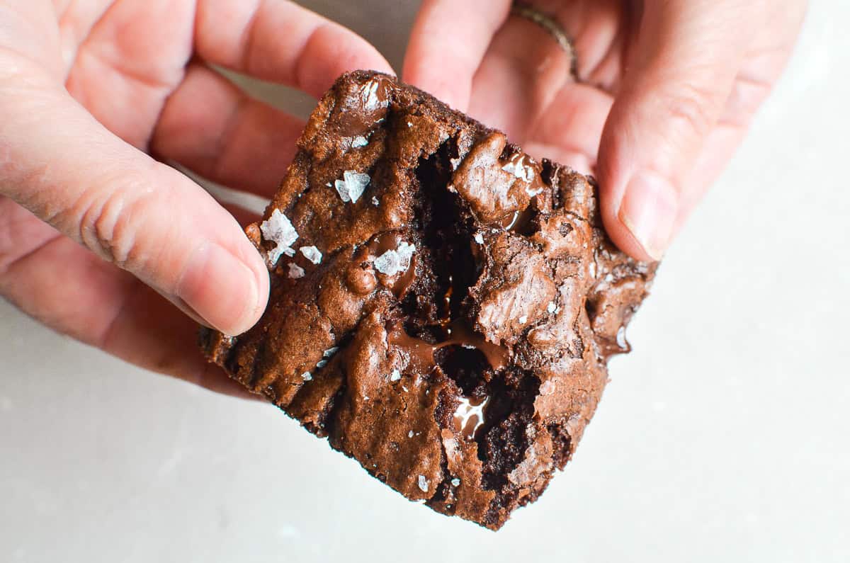 A pair of hands breaking apart a brownie.